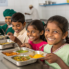 Volunteers serving nutritious mid-day meals to underprivileged school children in India through NGO support.